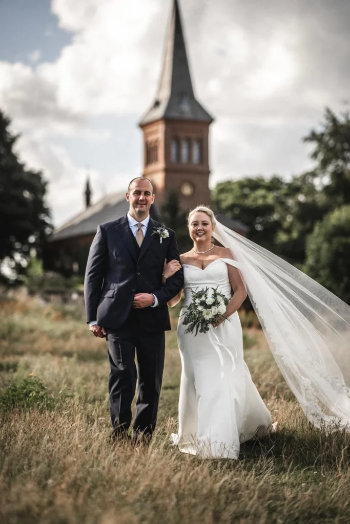Wedding couple in front of a church under an overcast sky