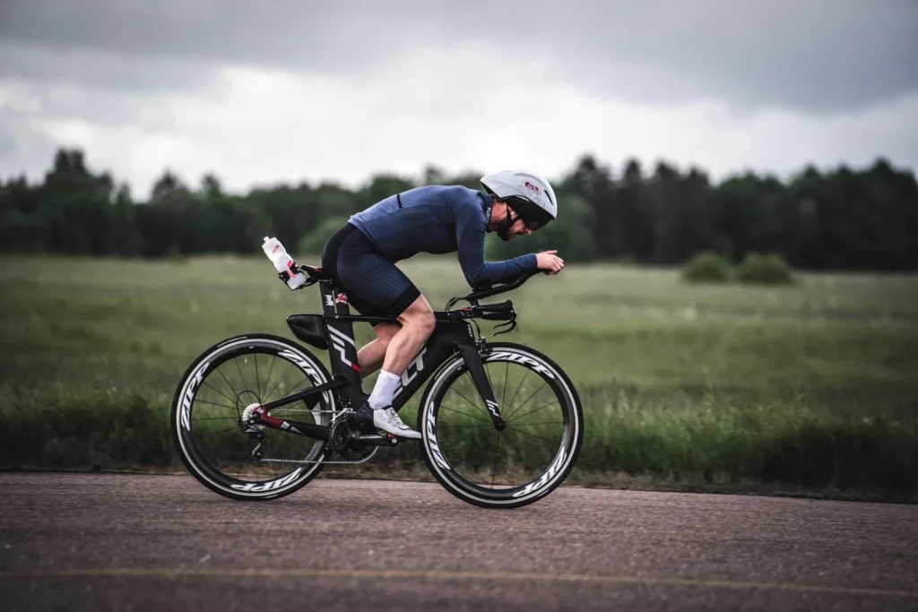 Cyclist in dark clothing on a country road beside a field Cyclist in dark clothing on a country road beside a field