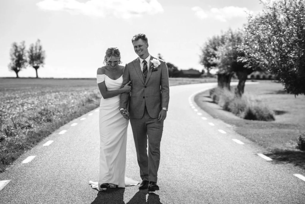 Wedding couple walking arm in arm on a country road in black and white