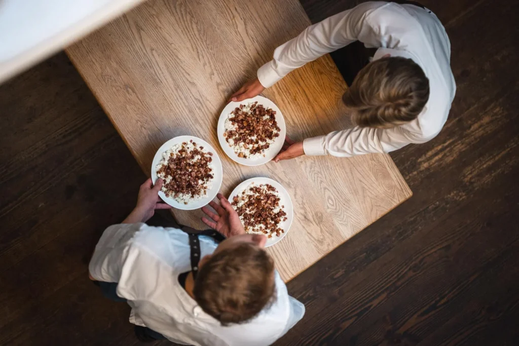 Two people preparing dessert plates seen from above Two people preparing dessert plates seen from above