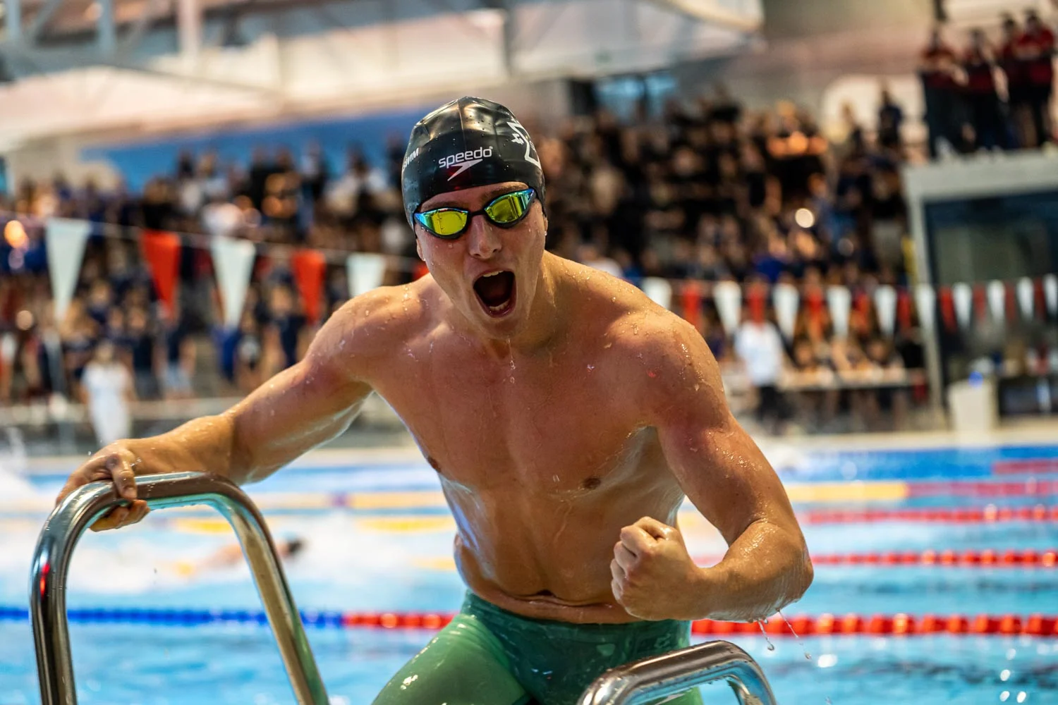 Swimmer wearing goggles holding a ladder beside the pool
