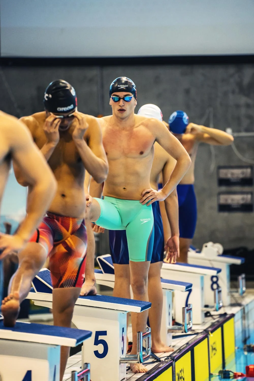 Swimmers gathered beside the pool starting blocks
