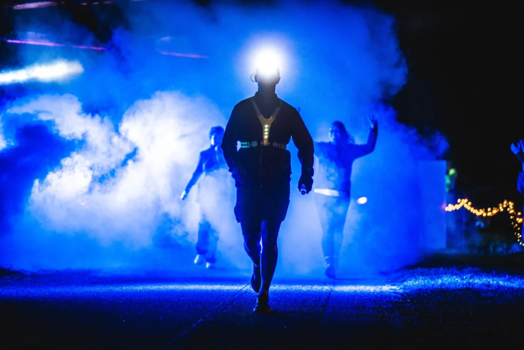 Runners wearing headlamps surrounded by blue smoke at night Runners wearing headlamps surrounded by blue smoke at night